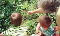 Elderly lady point out plants to two younger childre.