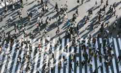 Aerial photo of a large crowd of people walking across a crossroads.
