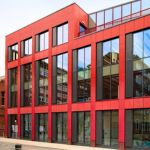 The Christabel Pankhurst Institute building. Red square building with large, rectangle glass windows.