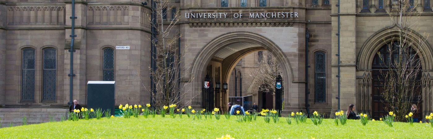 Photo of a University of Manchester campus building, with people walking in front.